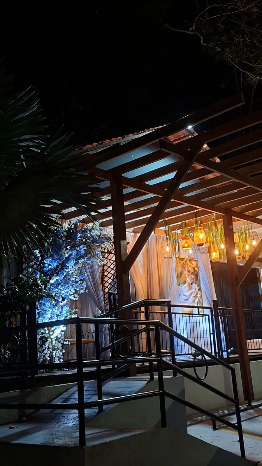 Terrace entrance at night, with a blue floral arch and lit rattan lamps